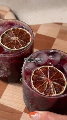 two glasses filled with liquid sitting on top of a cutting board next to each other