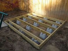 an unfinished wooden bed frame with cement bags in the middle and dirt on the ground