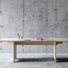 a wooden table sitting in front of a concrete wall