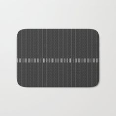 a black and white striped bath mat with grey stripes on the bottom, in front of a gray background