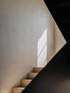 the stairs are made of wood and have light coming in from the window above them