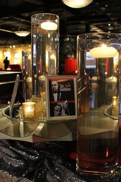 there are two vases with candles on the table next to each other and a photo