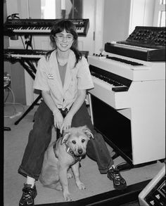 a woman sitting next to a dog in front of a keyboard and piano player's equipment