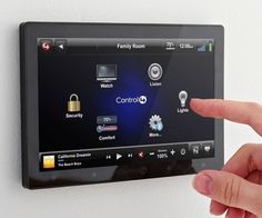 a person pointing at a touch screen on a wall mounted device with buttons and icons