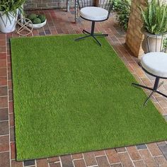 a green area rug in the middle of a patio with chairs and potted plants