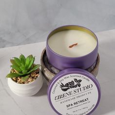 a candle next to a potted succulent plant on a white counter top