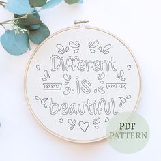 a cross stitch pattern with the words different is beautiful on it and some leaves around it