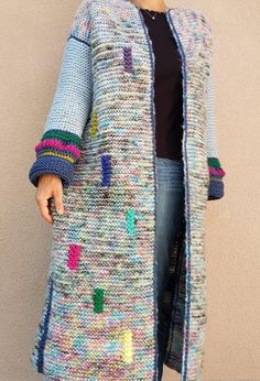 a woman is wearing a colorful knitted cardigan with holes in the front and sides