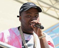 a man holding a microphone up to his mouth while wearing a hat and chain around his neck