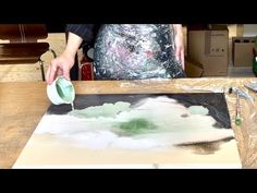 a person is painting on a table with paint rollers