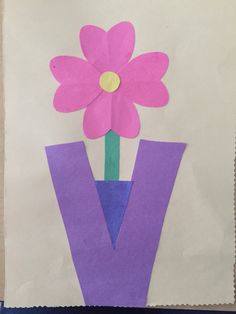 a paper bag with a flower in it and the letter v cut out from construction paper