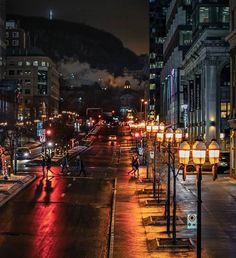 a city street at night with people walking on the sidewalk and cars driving down it