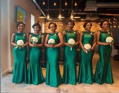 a group of women standing next to each other wearing green dresses and holding bouquets