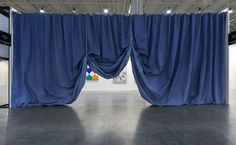 an empty room with blue drapes hanging from the ceiling and paintings on the wall