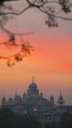 the sun is setting in front of a building with domes on it's roof