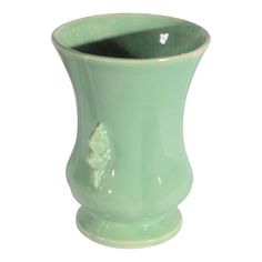 a green vase with a flower on the side