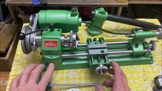 a person working on a green machine in a room with yellow and white checkered table cloth