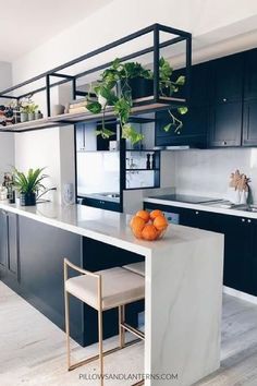 a kitchen with black cabinets and white counter tops, two stools in front of the island