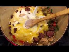 a skillet with sausage, mushrooms and cheese cooking on the stove top next to a wooden spatula