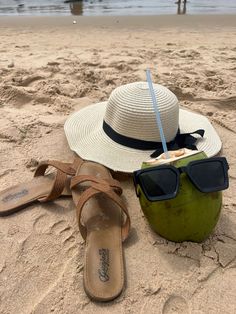 a hat, sunglasses and coconut on the beach