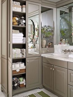 a bathroom with gray cabinets and lots of towels on the shelves in front of it