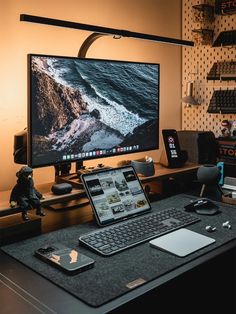 a computer desk with a laptop, keyboard and mouse on it in front of a monitor