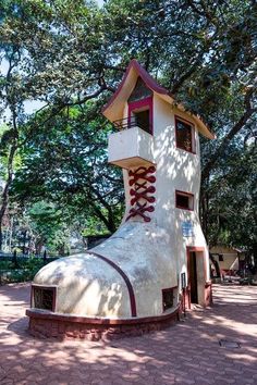 a white and red clock tower sitting in the middle of a park next to trees