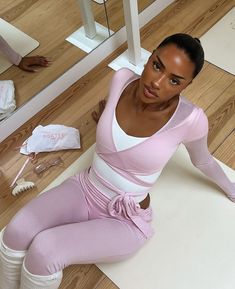 a woman is sitting on the floor in her pink outfit