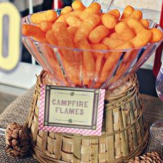 a basket filled with cheetos sitting on top of a table next to pine cones