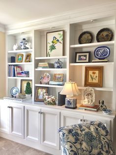 a living room filled with lots of furniture and bookshelves covered in pictures on top of white shelves