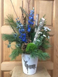 a potted plant with blue flowers and greenery in front of a wooden door