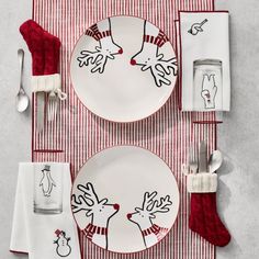 a christmas place setting with red and white striped napkins, silverware, and utensils