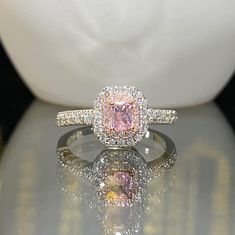 a pink diamond ring sitting on top of a table