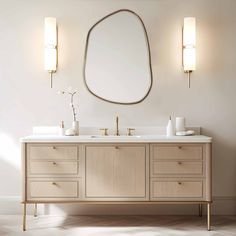 a bathroom vanity with two sinks and a large oval mirror above it, in front of a white wall