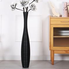 a tall black vase with white flowers in it