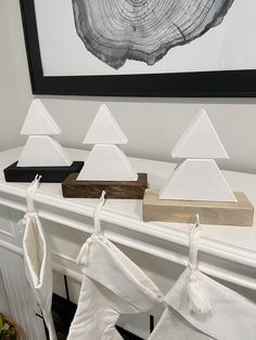 three white christmas stockings hanging on a mantel in front of a fireplace with pyramids