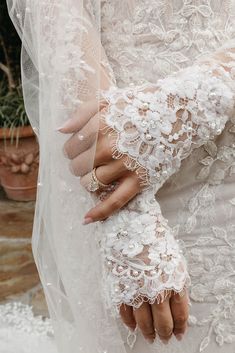 a close up of a person wearing a wedding dress with gloves on their arms and hands