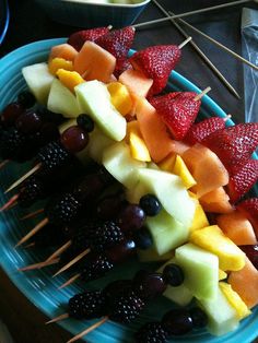 fruit skewers are arranged on a blue plate