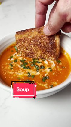 a person is dipping some bread into a bowl of soup with the word soup on it