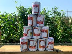 several cans of canned food stacked on top of each other in front of some bushes