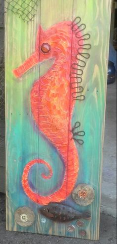 a wooden sign with a seahorse painted on it's side and some fish in the water