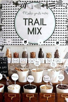 a table topped with lots of bowls filled with food next to a sign that says make your own trail mix