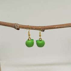 two green apples are hanging from gold - plated earwires on a branch