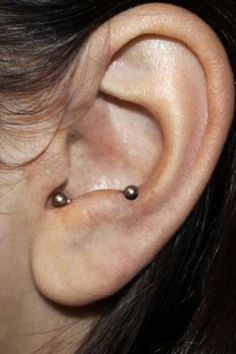 a woman's ear with two piercings on it