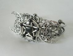 This beautiful silver plated filigree cuff bracelet has a silver plated triple moon design and a pewter silver pentacle with obsidian settings. Adjustable. Adjustable Gothic Metal Bracelets, Mystical Jewelry Bracelet Gift, Mystical Silver Jewelry For Festival, Handmade Adjustable Gothic Bracelet, Gothic Silver Jewelry For Festival, Gothic Silver Festival Jewelry, Handmade Adjustable Gothic Bracelets, Mystical Silver Jewelry With Intricate Design, Adjustable Silver Gothic Jewelry