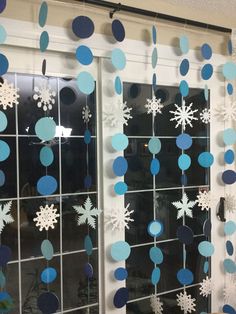 snowflakes hanging from the side of a window with blue and white decorations on it