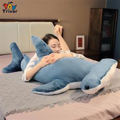 a woman laying on top of a blue shark pillow