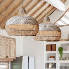 two wicker lamps hanging from the ceiling in a kitchen with white walls and cabinets