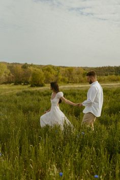 a man and woman are holding hands in a field