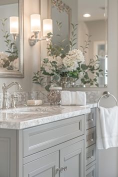 a bathroom with two sinks, mirrors and flowers in vases on the counter top